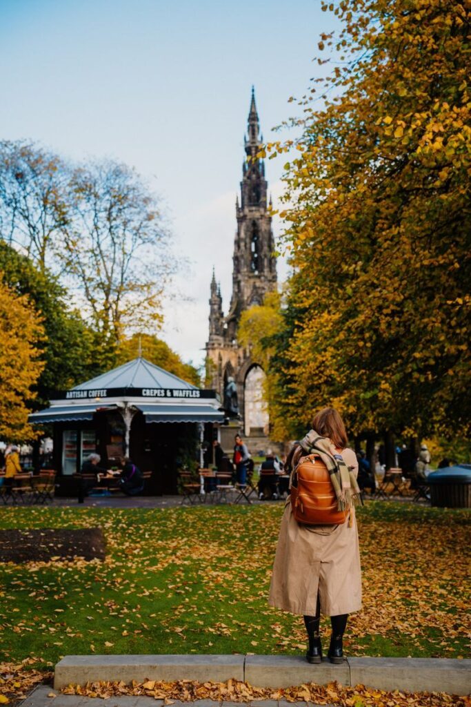 Woman with backpack enjoys an autumn day at Scott Monument in Edinburgh.
