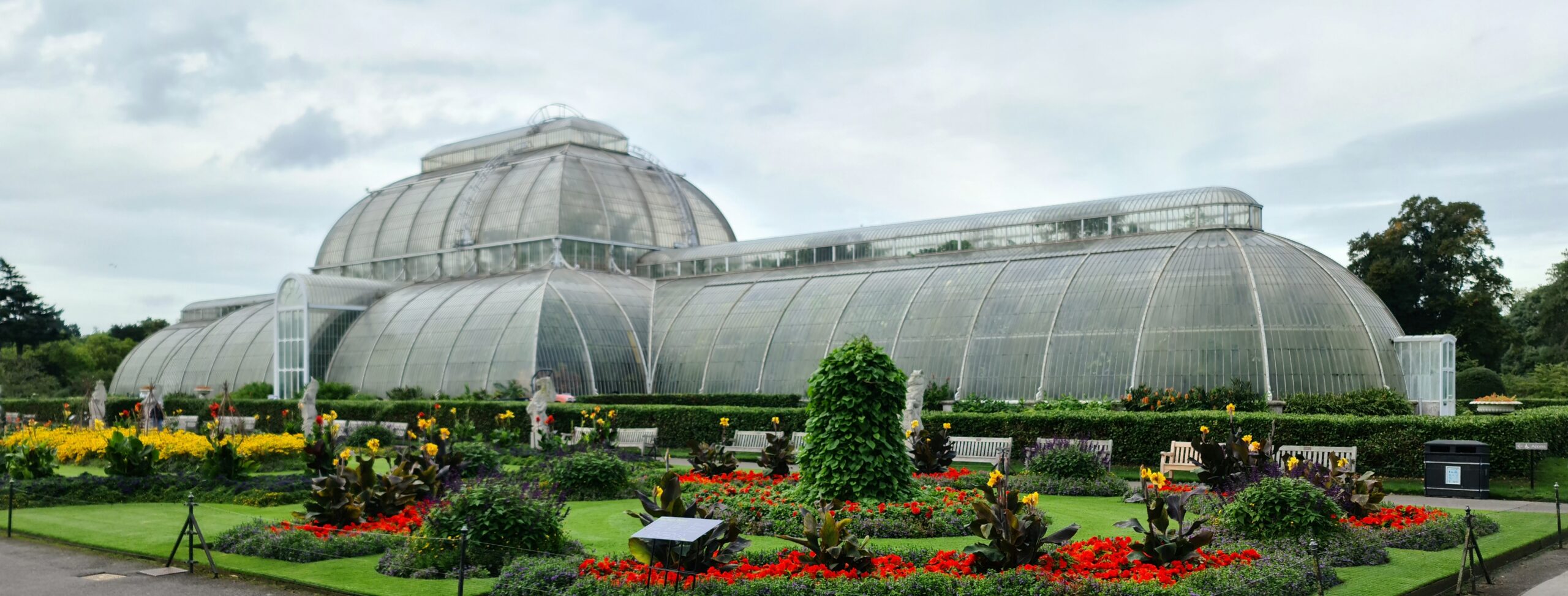 The glass and iron Palm House at Kew Gardens surrounded by botanical grounds