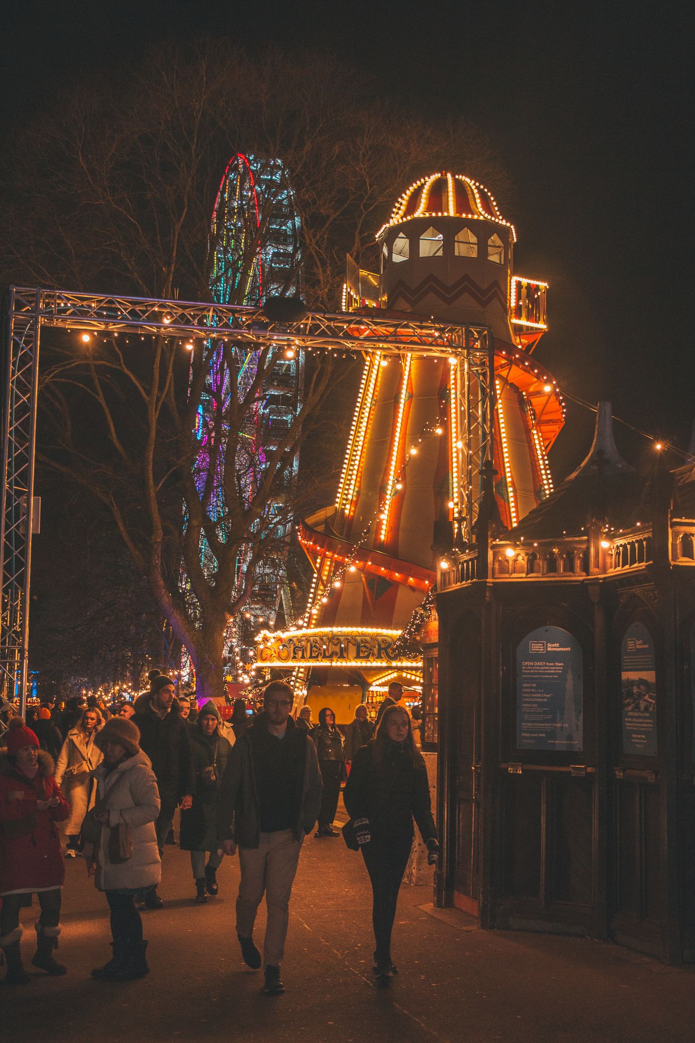 Edinburgh Christmas Market illuminated at night with fairground rides and festive lights