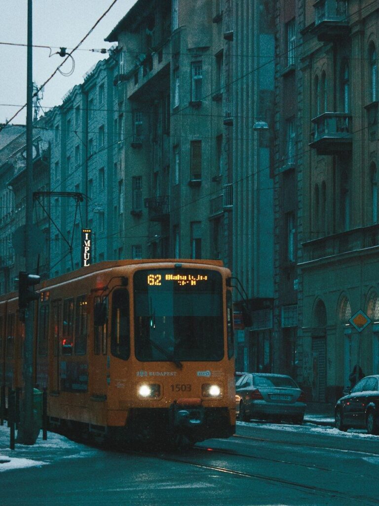An orange tram passes through a city street